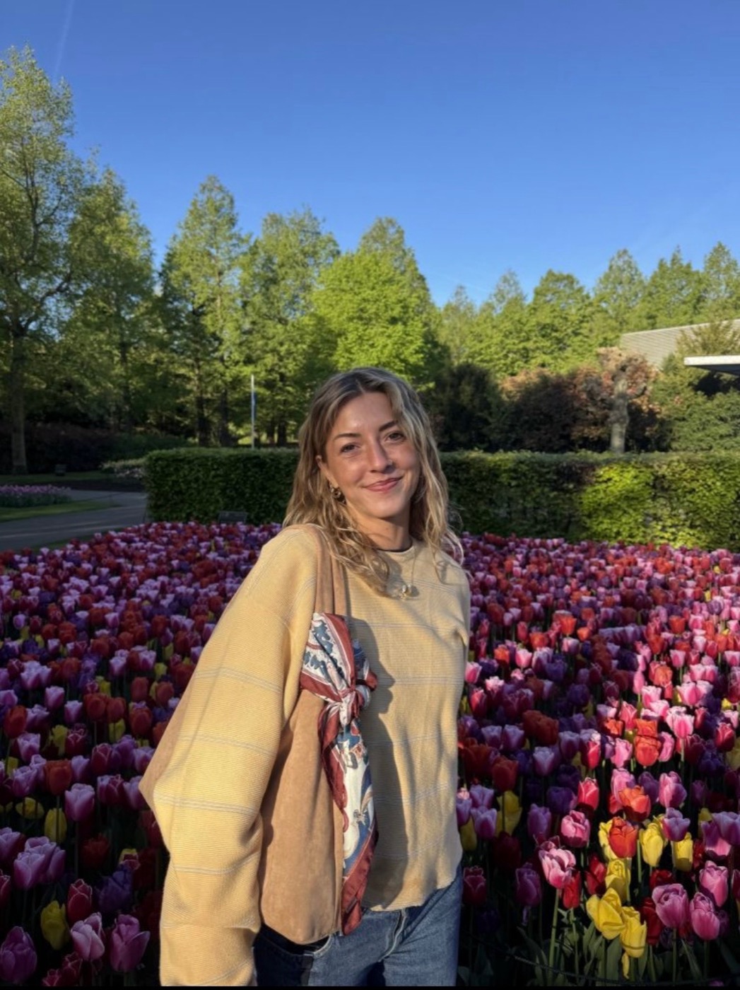 Meg Allen smiling in front of a vibrant tulip garden in the Netherlands